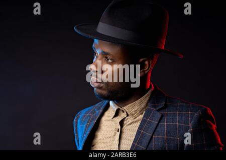 Taille up Studio Portrait von jungen gutaussehenden, selbstbewussten, unrasierten afrikanischen Geschäftsleuten, mit Hemd, kariertem Anzug gegen dunkle Backgroschen Stockfoto