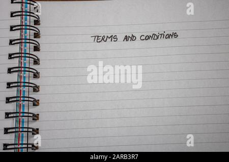 Geschäftsbedingungen, Handschriftertext auf der Büro-Agenda, Büro-Spiralnotizbuch. Kopierbereich. Stockfoto