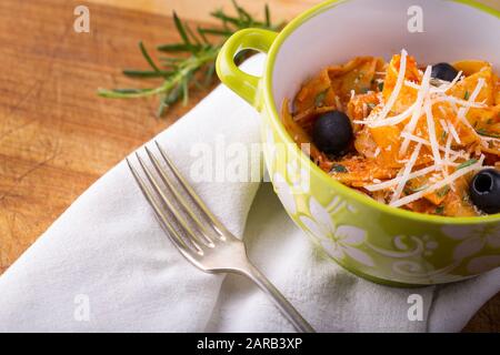 Italienische Pasta mit Tomatensauce, geriebenem Käse und Rosmarin mit Gabel und Tuch. Stockfoto