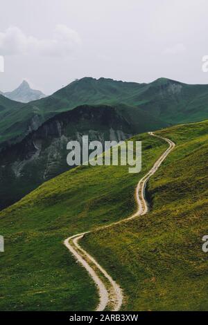 Ein Fußweg durchschneidet die grüne Ackerlandlandschaft von Stoos, Morschach, Schwyz, Schweiz EU - Schweizer Alpen Sommerberglandschaft Stockfoto