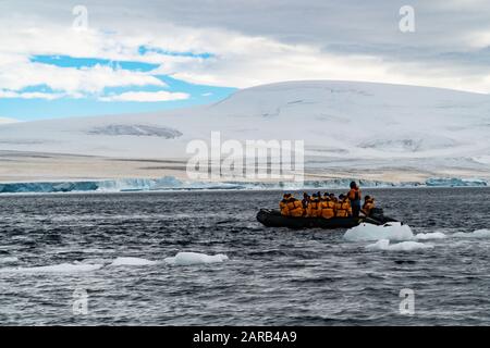 Touristen auf einem Schlauchboot aus dem Gummi-Tierkreis, der durch Eisschollen in den kalten Gewässern der Antarktis segelt Stockfoto