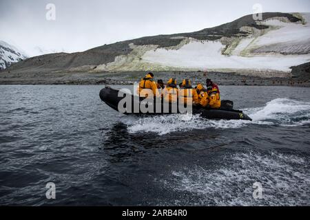 Touristen auf einem Schlauchboot aus dem Gummi-Tierkreis, der durch Eisschollen in den kalten Gewässern der Antarktis segelt Stockfoto