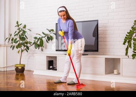 Schöne schwangere Frau putzt gern ihr Haus. Stockfoto