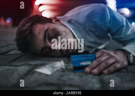 Drogenabhängiger Mann liegt in Schmerzen am Boden Stockfoto