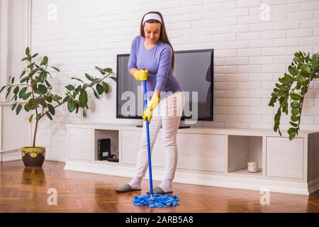 Schöne schwangere Frau putzt gern ihr Haus. Stockfoto