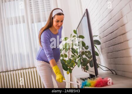 Schöne schwangere Frau putzt gern ihr Haus. Stockfoto