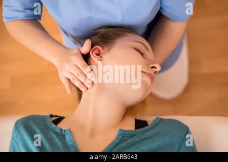 Physiotherapeutin oder Chiropraktikerin, die den Hals des Patienten verstellt. Physiotherapie, Rehabilitationskonzept. Draufsicht Nahaufnahme. Stockfoto