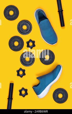 Vertikaler Hintergrund für Sport. Hanteln und Turnschuhe auf gelbem Hintergrund. Flaches Layout, Draufsicht, Kopierbereich. Stockfoto