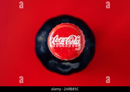 Charkiw, Ukraine, 14. November 2019: Glasflasche Coca-cola auf rotem Hintergrund. Draufsicht. Runder Kork mit Wassertropfen, Kondensat. Originalgetränk Stockfoto