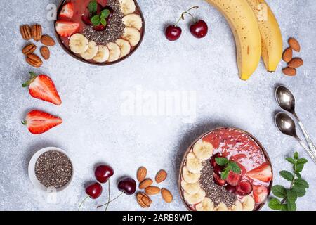 Gesundes Frühstück smoothie Schüssel mit Erdbeeren, Kirschen, Chia Samen auf grauem Beton Hintergrund. Blick von oben. Kopieren Sie Platz Stockfoto