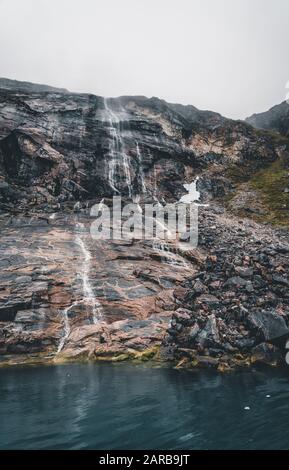 Panoramablick auf den schönen Wasserfall, der von einem hohen Bergfjord im Westen Grönlands nördlich von Ilulissat kommt. Stockfoto