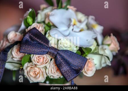 Ein farbenfroher Blumenstrauß mit pinkfarbenen Ponys und pfriechigen und gelben Rosen mit schwarzer Krawatte. Details zur Hochzeit. Stockfoto