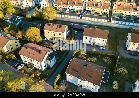 Luftbild von Wohnhäusern mit roten Dächern und Straßen mit geparkten Autos in ländlicher Stadtgegend. Ruhige Vororte einer modernen europäischen Stadt. Stockfoto