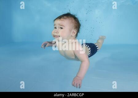 Kleiner Baby-Junge lernt unter Wasser zu schwimmen. Baby schwimmend unter Wasser im Pool. Gesunder Familienleben und Wassersport für Kinder. Kind d