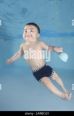 Kleiner Baby-Junge lernt unter Wasser zu schwimmen. Baby mit Spielzeug Schwimmen unter Wasser im Pool. Gesunder Familienleben und Wassersport für Kinder
