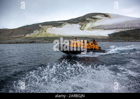 Touristen auf einem Schlauchboot aus dem Gummi-Tierkreis, der durch Eisschollen in den kalten Gewässern der Antarktis segelt Stockfoto