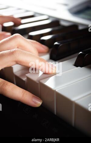 Nahansicht der Kinderhände, die auf den Klaviertasten des elektronischen Synthesizers spielen. Vertikales Foto bereit für Musikgeschäfte, Poster, Werbehefte, Bus Stockfoto