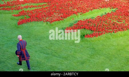 Beefeater zu Fuß durch die Kunst der Installation Blut fegte Länder und Meere von Rot am Tower von London. Stockfoto