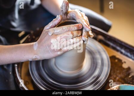 Potter, der an einem Potter-Rad arbeitet und eine Vase macht. Frau, die den Ton mit ihren Händen formt und in einer Werkstatt Kanne schafft. Nahaufnahme Stockfoto