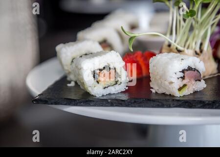 Sushi rollen japanische Speisen auf schwarzem Teller. Sushi-Rollset mit Lachs, Kaviarreis und Gemüse. Japanische Restaurantkarte. Stockfoto