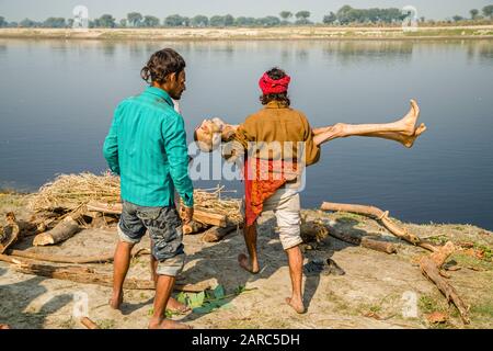 Waschen eines Sterbekörpers im Wasser des Flusses Yamuna im Rahmen einer Kremationsfeier Stockfoto