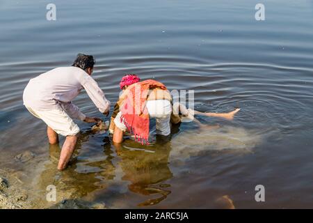 Waschen eines Sterbekörpers im Wasser des Flusses Yamuna im Rahmen einer Kremationsfeier Stockfoto