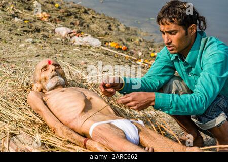 Im Rahmen einer Feuerbestattung einen Todeskörper auf Brennholz an den Ufern des Flusses Yamuna legen Stockfoto