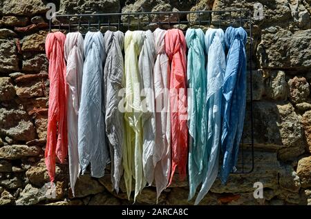 Eine Sammlung von verschiedenen Schals, die Stoffe an einem Rack hängen Stockfoto