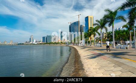 Luanda, ANGOLANISCHER Zeit - 15. Dezember 2019: Menschen, die an einem sonnigen Tag in der Bucht von Luanda spazieren gehen. Redaktionelle Illustration. Stockfoto