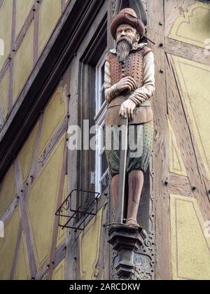 Ein architektonisches Detail einer Holzschnitzerei eines mittelalterlichen Mannes mit Bart an der Seite des alten Gebäudes in Riquewihr, Elsaß-Frankreich Stockfoto