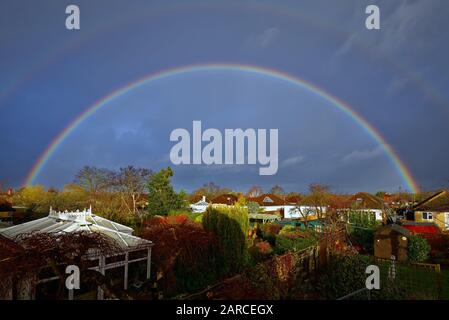 Ein vollständiger Regenbogen bildete sich über den Dächern von Vorstadthäusern in Shepperton Surrey England UK Stockfoto