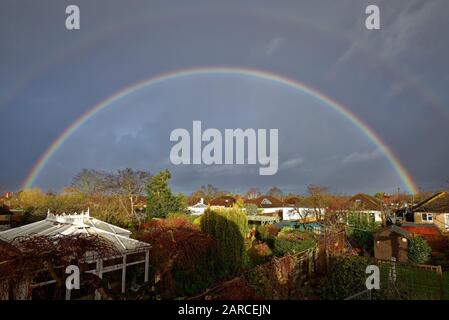 Ein vollständiger Regenbogen bildete sich über den Dächern von Vorstadthäusern in Shepperton Surrey England UK Stockfoto