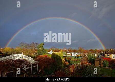 Ein vollständiger Regenbogen bildete sich über den Dächern von Vorstadthäusern in Shepperton Surrey England UK Stockfoto