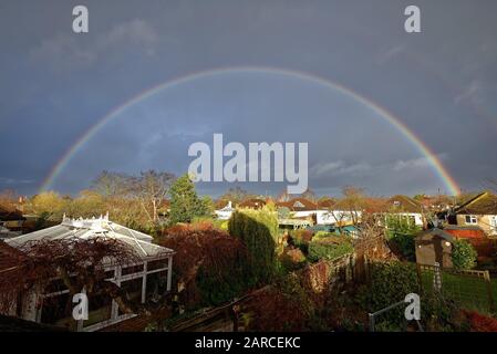 Ein vollständiger Regenbogen bildete sich über den Dächern von Vorstadthäusern in Shepperton Surrey England UK Stockfoto