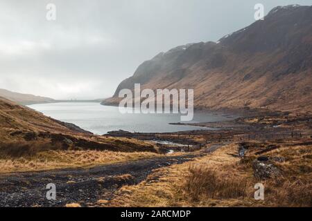 Der schottische Wasserreservoir Lochan na Lairige mit dem schottischen Hydro am Horizont an einem nebligen Wintertag. Stockfoto