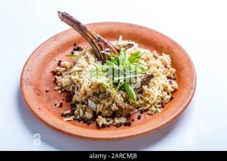 Lammrippe mit Reis auf einer Tonplatte, auf weißem Grund Stockfoto