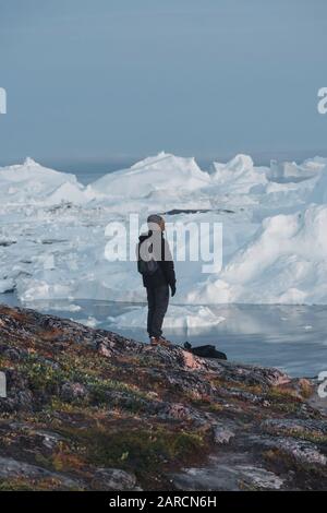 Entdecker von Grönlandtouristen mit Blick auf Icefjord in Ilulissat. Reisen Sie mit Eisbergen in arktischer Natur. Tourist, der auf erstaunlich schaut Stockfoto
