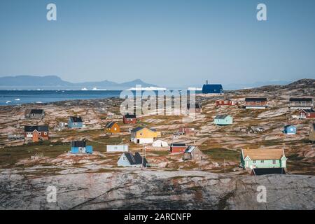 Typisches farbenfrohes blaues Fischerhaus aus Holz mit Eisberg im Gebiet der Disko-Bucht Grönland und Ilulissat. Typische Architektur im arktischen Kreis. Sommer Stockfoto