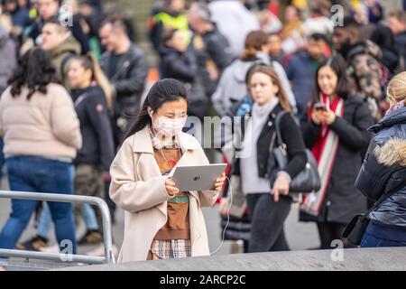 London, 26. Januar 2020. Chinesische Frauen tragen Gesichtsmaske mit Tablet in der belebten Straße von london Stockfoto