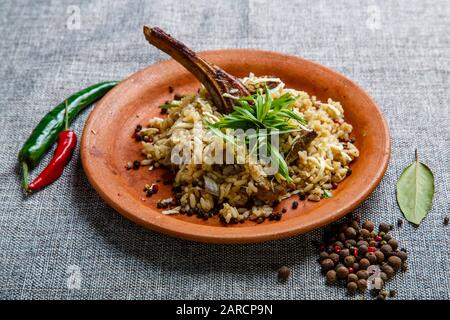 Lammrippe mit Reis auf einer Tonplatte. Strukturierte graue Leinwand. Stockfoto