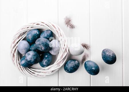 Gruppe hellblauer Eier in ihrem Gelege auf weißem Holzhintergrund. Fröhliche Osterdekoration Stockfoto