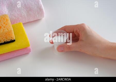 Reinigungskonzept. Waschmittel für den Reinigungsraum. Halten Sie einen Kunststoff-Messbecher mit körnigem Reinigungsmittel und Stofftüchern in der Hand. Aufgaben der Hausfrau. Stockfoto