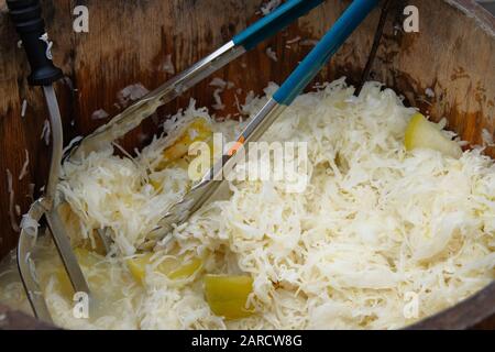 Sauerkraut mit Äpfeln in Holzfass wird auf dem lokalen Markt nach Gewicht verkauft. Fermentiert konserviertes vegetarisches Konzept für gesundes Essen. Stockfoto