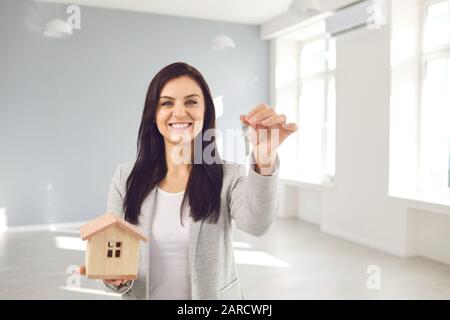 Realtor Agent ist ein Realtor mit Schlüsseln in der Hand vor dem Hintergrund eines weißen Wohnzimmerwohnhauses. Stockfoto