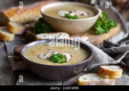 Köstliches hausgemachtes Suppenpüree mit portobello und Wildpilzen auf rustikalem Tisch Stockfoto