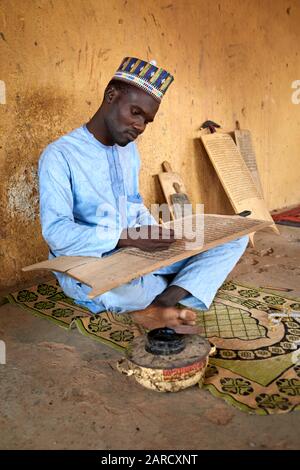 Muslimischer Mann, der korankalligraphie auf einer Holztafel praktiziert. Stockfoto