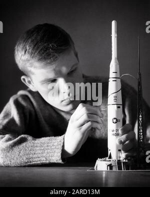 1960ER JAHRE ABSICHT TEENAGER-GEBÄUDE DETAILLIERUNG MODELL DER MEHRSTUFIGEN STARTFAHRZEUG-RAKETE - J11257 CLE003 HARS VEREINIGTE STAATEN VON AMERIKA MÄNNER TEENAGER-JUNGE AUSDRÜCKE B&W NORDAMERIKA ZIELE NORDAMERIKA TRÄUME KOPF UND SCHULTERN ABENTEUER HOBBY HOFFNUNG SPANNUNG BERUFE VERBINDUNG TAGTRAUM IMAGINATION RAKETEN TEENAGER-KREATIVITÄT INTENSIV JUNGEN SCHWARZ UND WEISSE KAUKASISCHE ETHNIE IST ALTMODISCH Stockfoto