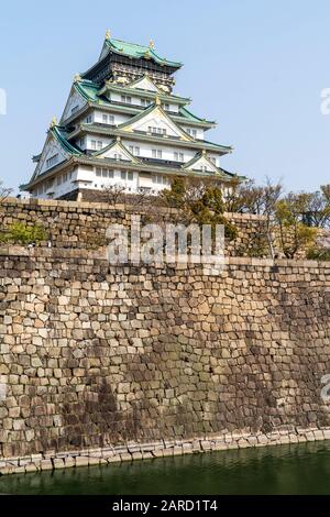 Der Berghof im Borogata-Stil der Burg Osaka und die massiven Steinmauern Ishigaki und der Mote, vom Nishinomaru-Garten aus gesehen gegen einen klaren blauen Himmel. Stockfoto