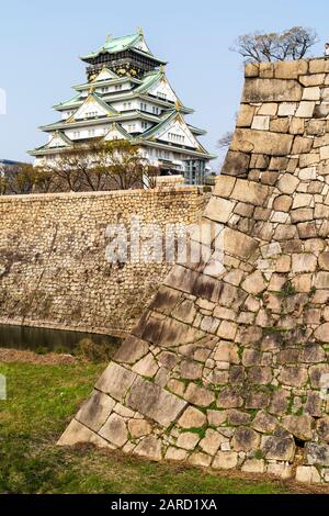 Der Berghof im Borogata-Stil der Burg Osaka und die massiven Steinmauern Ishigaki und der Mote, vom Nishinomaru-Garten aus gesehen gegen einen klaren blauen Himmel. Stockfoto