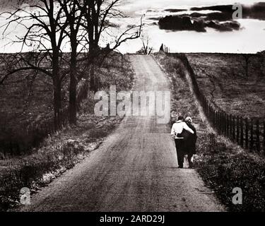 1960ER JAHRE RÜCKANSICHT REIFER PAARARM IN ARM GEHEN EINSAME STRASSE UNFRUCHTBARE HERBSTLANDSCHAFT MIT OMINÖSEN WOLKEN AM HORIZONT - R2777 HAR001 HARS NOSTALGIE ALTE MODE 1 ANGST EINSAME JUNGE ERWACHSENE ÄRGER SORGEN STARKE LEBENSFÜHRUNG FRAUEN VERHEIRATETE MOODY LÄNDLICHE EHEGATTEN HAUSLEBEN KOPIE RAUMFAHRT FREUNDSCHAFT DURCHGEHENDE DAMEN MENSCHEN INSPIRATION FÜRSORGLICHE MÄNNER SYMBOLE GELASSENHEIT SPIRITUALITÄT BEUNRUHIGT B&W BETROFFENER PARTNER TRAURIGKEIT WOLKEN TRÄUME HORIZONT HOHE WINKEL SILHOUETTIERTE ARM IN DER ARMERHOLUNG STIMMUNG OMINÖSE BEZIEHUNGEN KONZEPT KONZEPT GELÄUT ENTWEICHEN ANONYMER PERSÖNLICHER BINDUNG SYMBOLISCHE ZUNEIGUNG Stockfoto